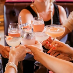 Cocktails, several women hold different cocktail glasses together in a circle and clink glasses