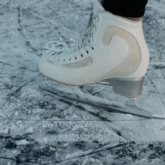 A skate on the foot of a person stands on the frozen ice.