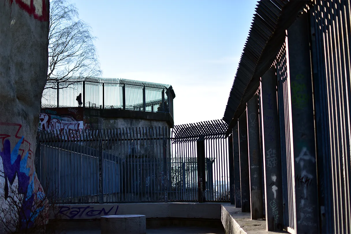 View of the flak tower at Gesundbrunnen in Humboldthain. The sun is shining against the light and the high fences are beautifully silhouetted.