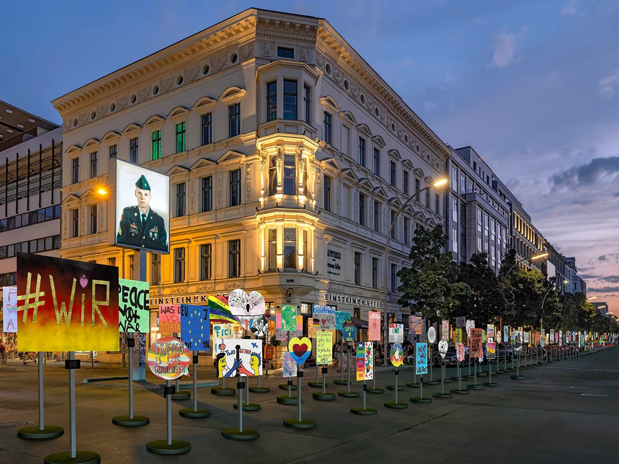 View of Checkpoint Charlie in Berlin. Various posters are lined up next to each other in front of the border crossing. They are intended to symbolize and express the thoughts, feelings etc. on the anniversary of 35 years since the fall of the Wall.