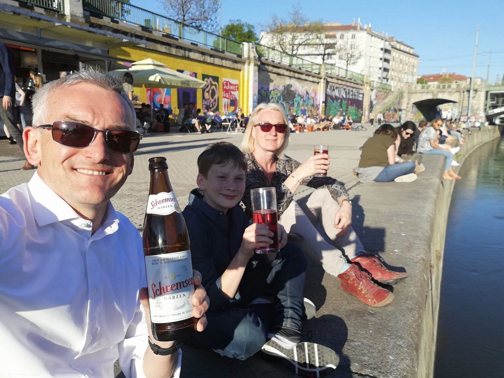 Danube canal, family sitting on the Danube canal enjoying the sun, all holding a drink and smiling at the camera