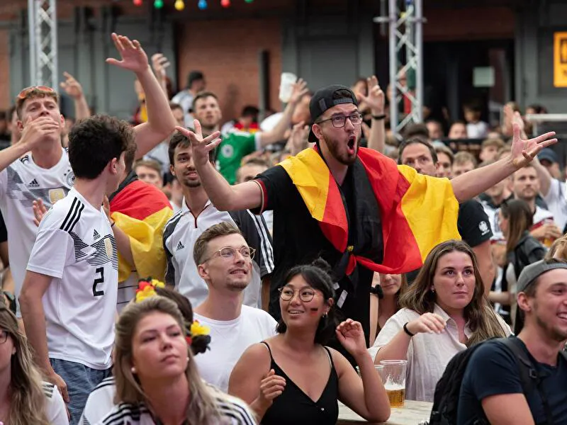 Fußballfans mit Deutschlandfahne jubeln und schreien