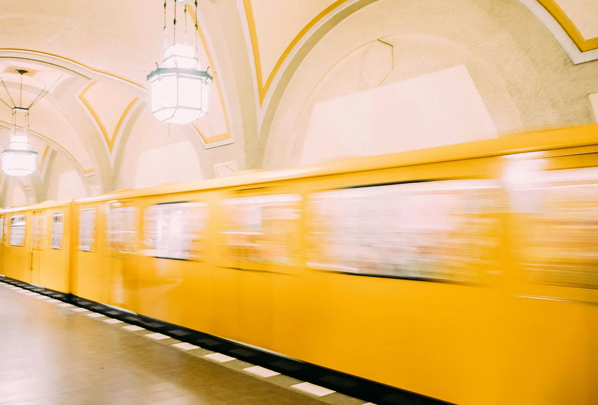 Gelbe U-Bahn fährt durch den Bahnhof, verschwommen, da die Bewegung dargestellt wird