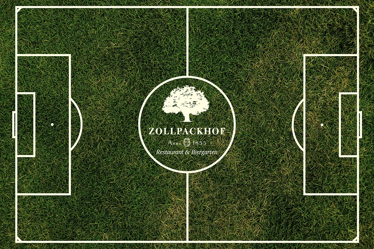 Zollpackhof, view of a grass field from above, the lines of the soccer field are drawn, in the middle is the Zollpackhof logo