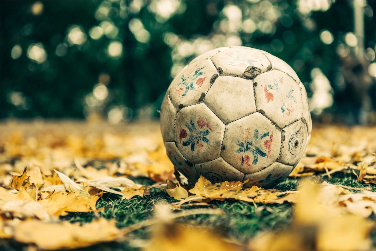 old soccer ball lying in yellow leaves, background blurred