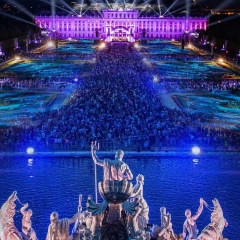 Summer night concert of the Vienna Philharmonic Orchestra, evening atmosphere, the palace garden is colorfully illuminated, guests stand in the palace garden