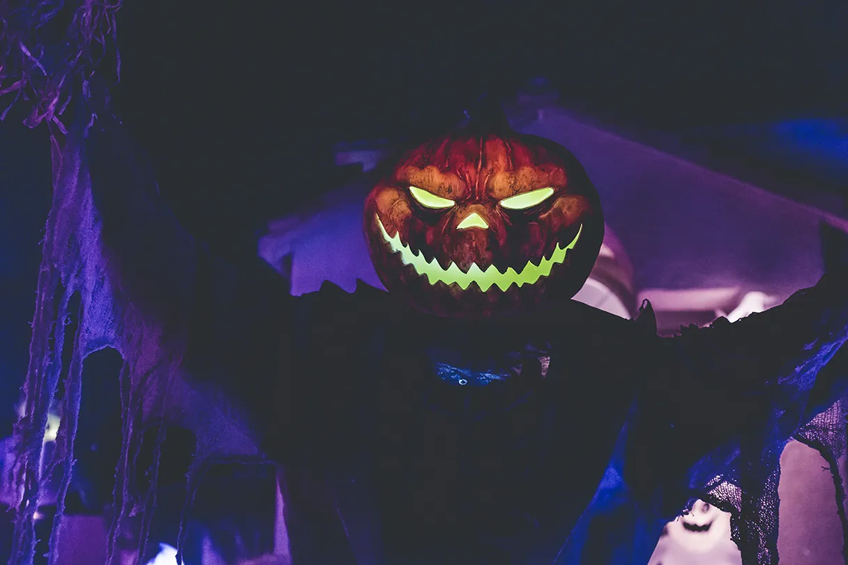 Halloween, a person has a pumpkin on his head with a glowing eye, nose and mouth, dark purple background, gloomy mood