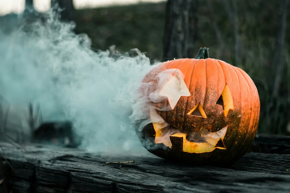 Carved pumpkin lying on the floor and smoke coming out of the pumpkin's head, creepy atmosphere