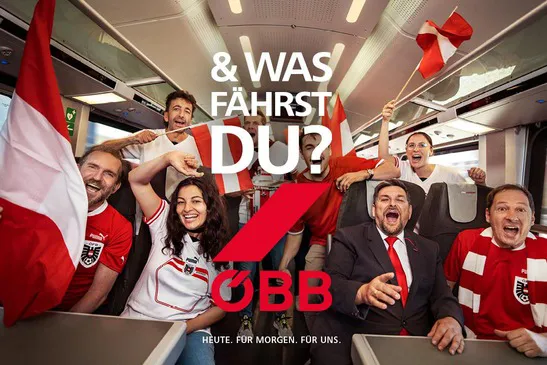ÖBB Fußballfans sitzen in der Bahn und jubeln mit österreich Fanschmuck in rot weiß