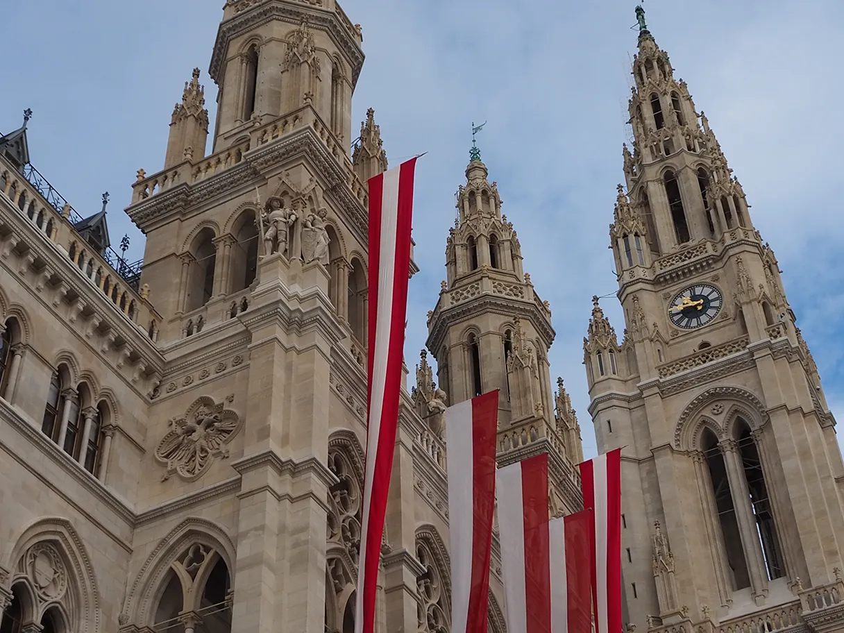 Wiener Rathaus mit österreichischen Flaggen behangen, blauer Himmel weiße Schleierwolken