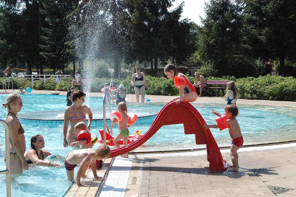 Kinderbad, Freibad, Kinder spielen an einer kleinen roten Wasserrutsche, Mütter stehen drum herum