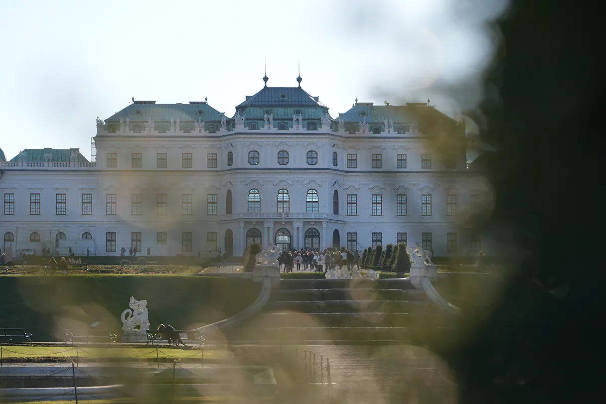 View of the upper Belvedere. There are a few people on the steps in front of the museum.