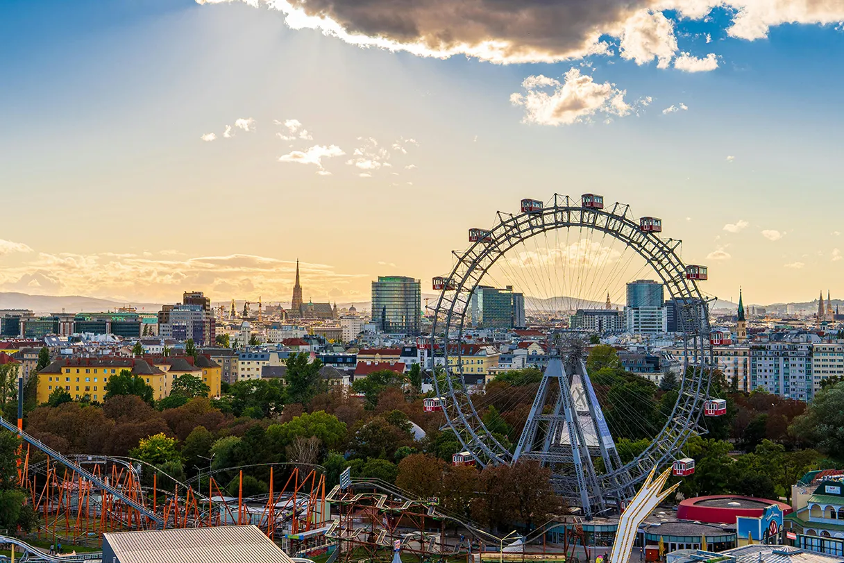 View over Vienna at sunset. The Vienna Giant Ferris Wheel is in the foreground. St. Stephen's Cathedral can be seen in the distance.