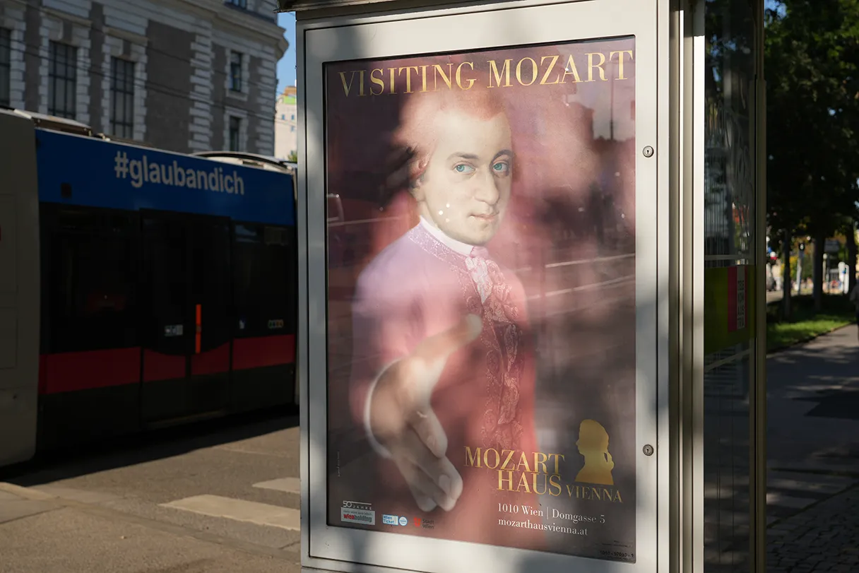 Mozarthaus Vienna, Wien, Plakat an der Straße, Straßenbahn fährt im Hintergrund vorbei