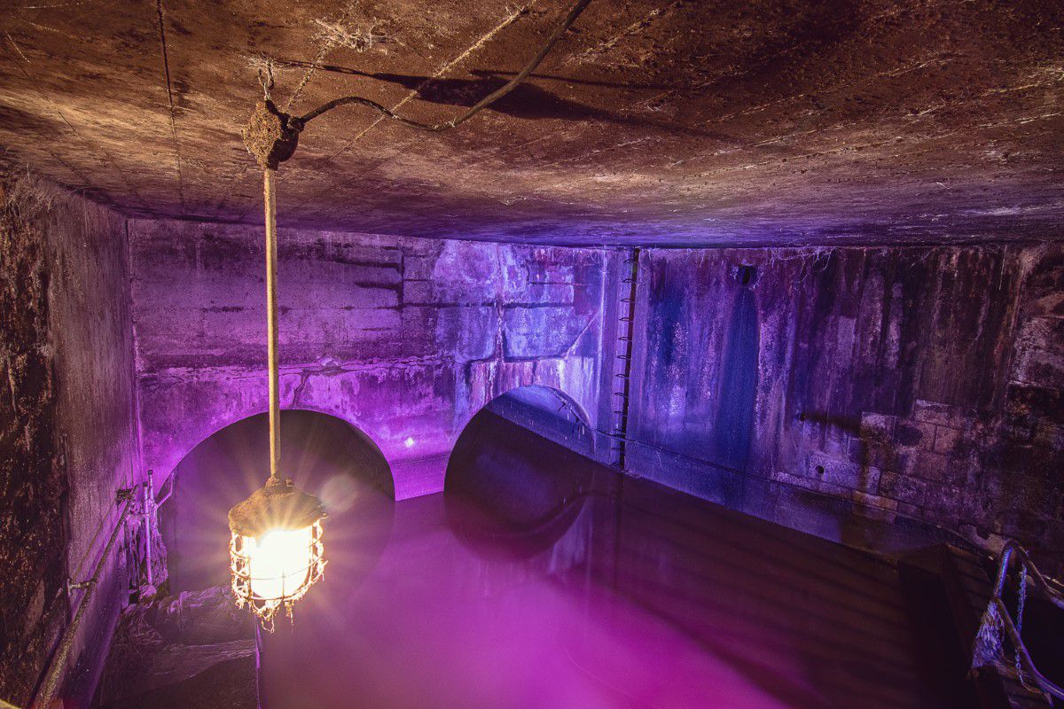 3. Mann Tour, Tunnel, Kanalisation, Deckenlampe leuchtet in pink angestrahltes Wasser