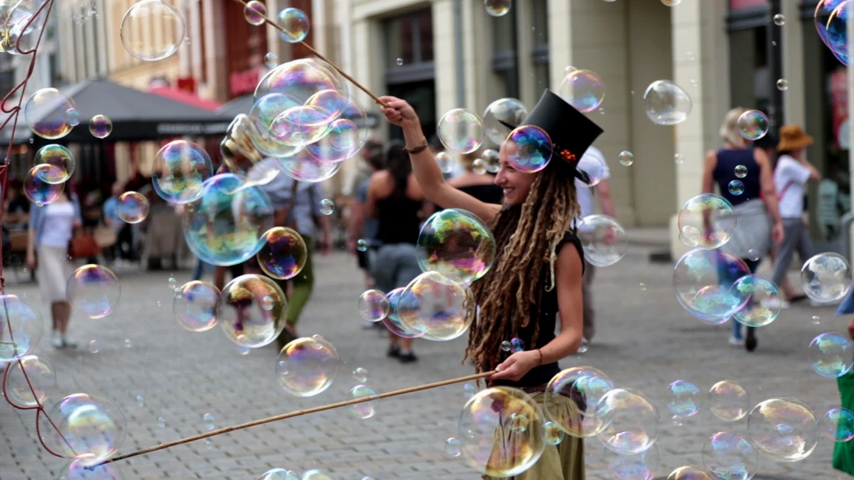 Woman with hat makes big soap bubbles
