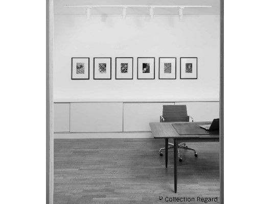 Salon Photographique, schwarz weiß Aufnahme, Raum, Tisch und Stuhl halb zu sehen, Bilder an der Wand