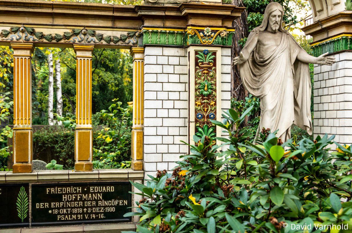 Grab Familie Hoffmann, gelb-goldene Säulen, Jesus Statue am rechten Bildrand, grüner Oleanderbusch im Vordergrund