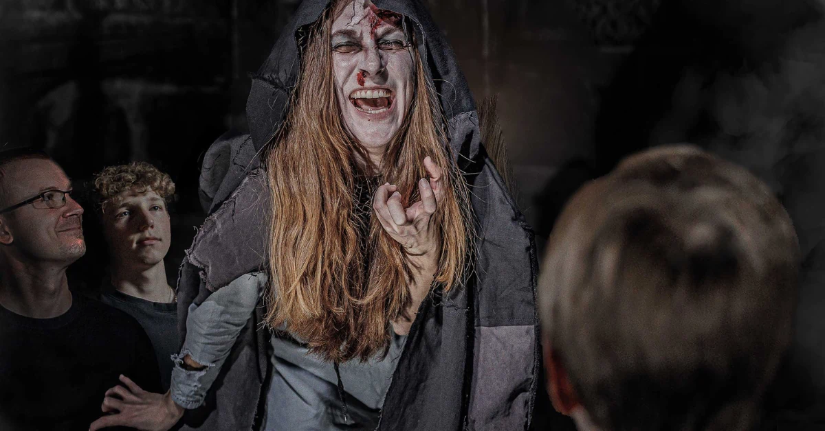 Berlin Dungeon, eine als Hexe verkleidete Frau mit Blutspuren im Gesicht erschreckt die Besucher
