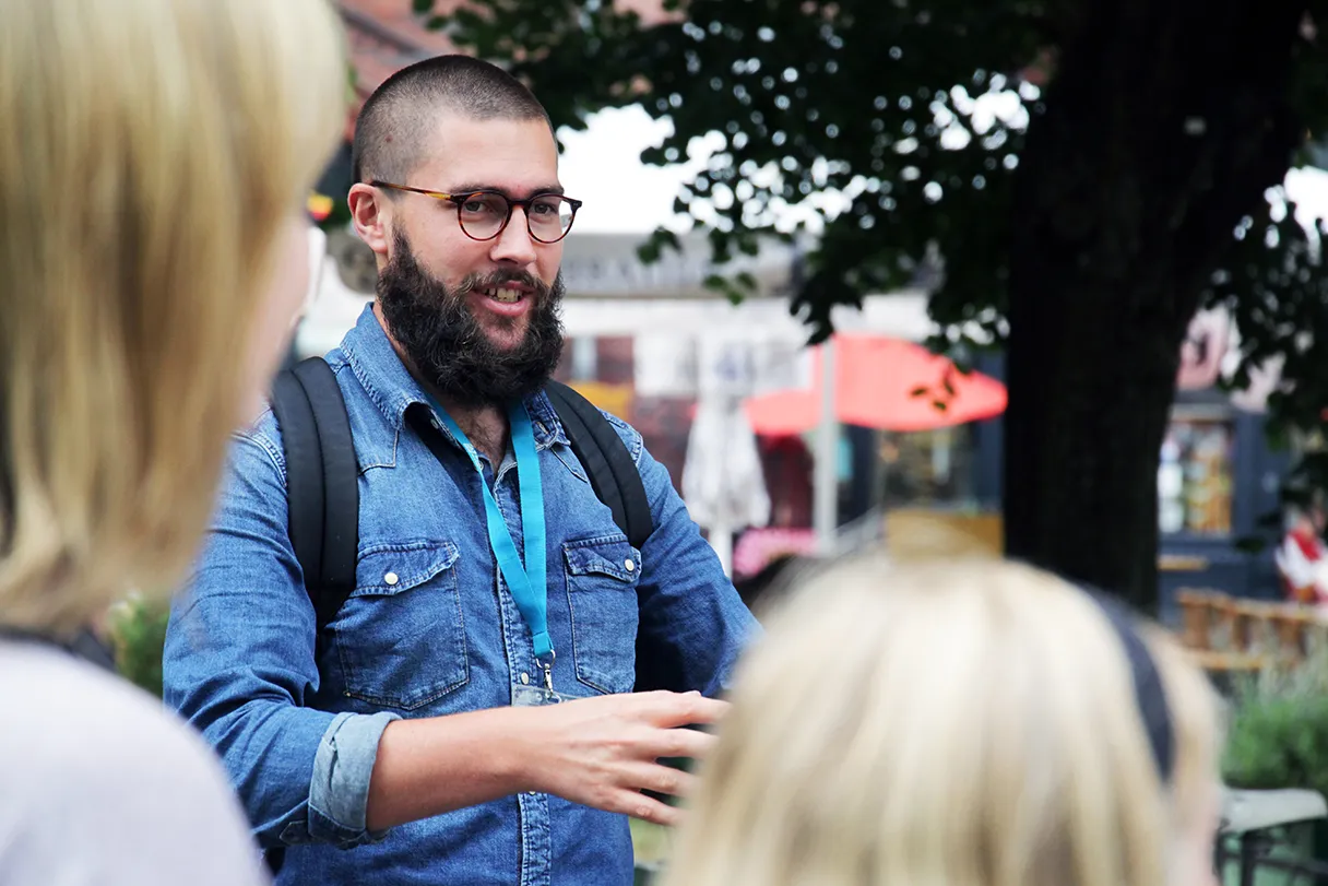 Original Berlin walks, Guide im blauen Jeanshemd und schwarzem Bart erklärt der Gruppe während der Tour die Sehenswürdigkeiten Berlins