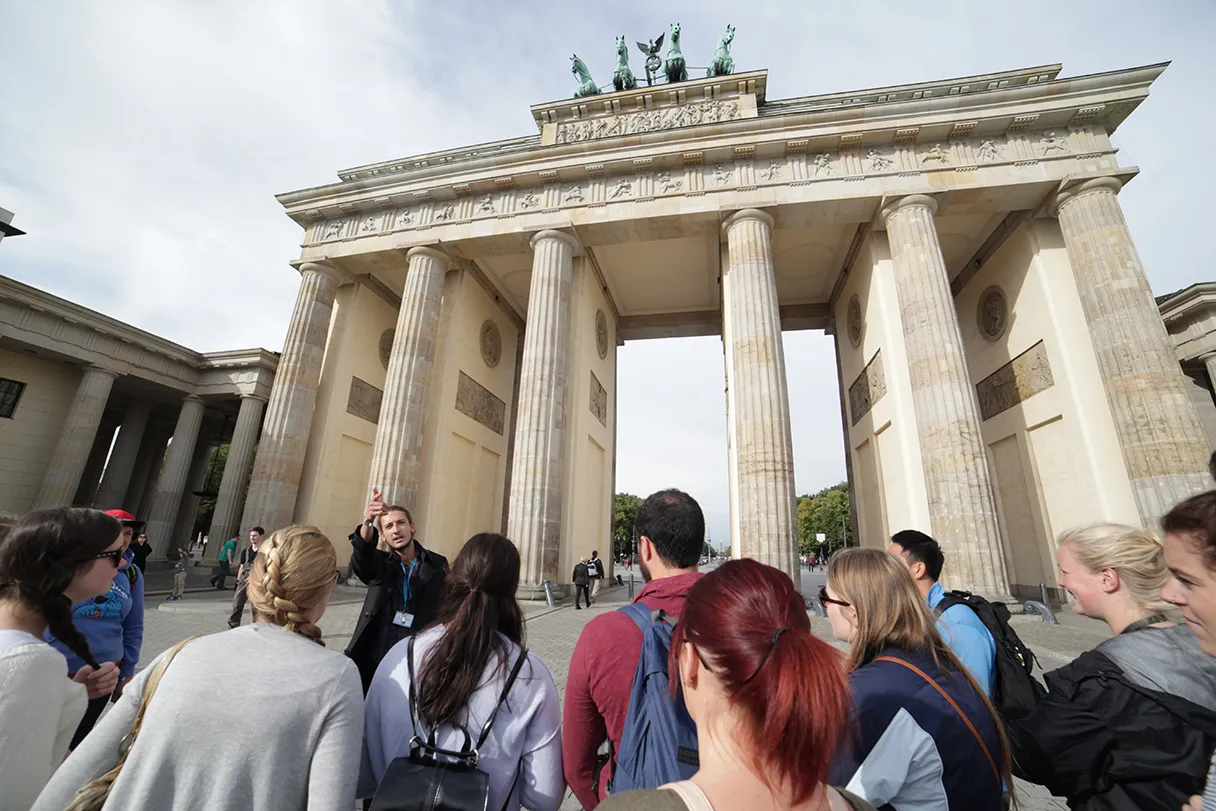 Original Berlin walks, Brandenburger Tour, Gruppe steht mit dem Guide vor dem Brandenburger Tor und blickt in Richtung Siegessäule