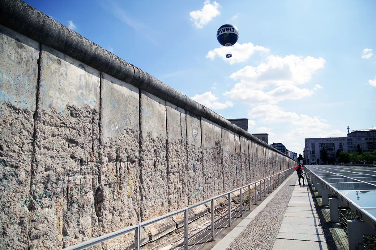Original Berlin walks, Blick auf die Berliner Mauer auf dem Gelände Topographie des Terrors, Heißluftballon ist im Hintergrund am blauen Himmel zu sehen