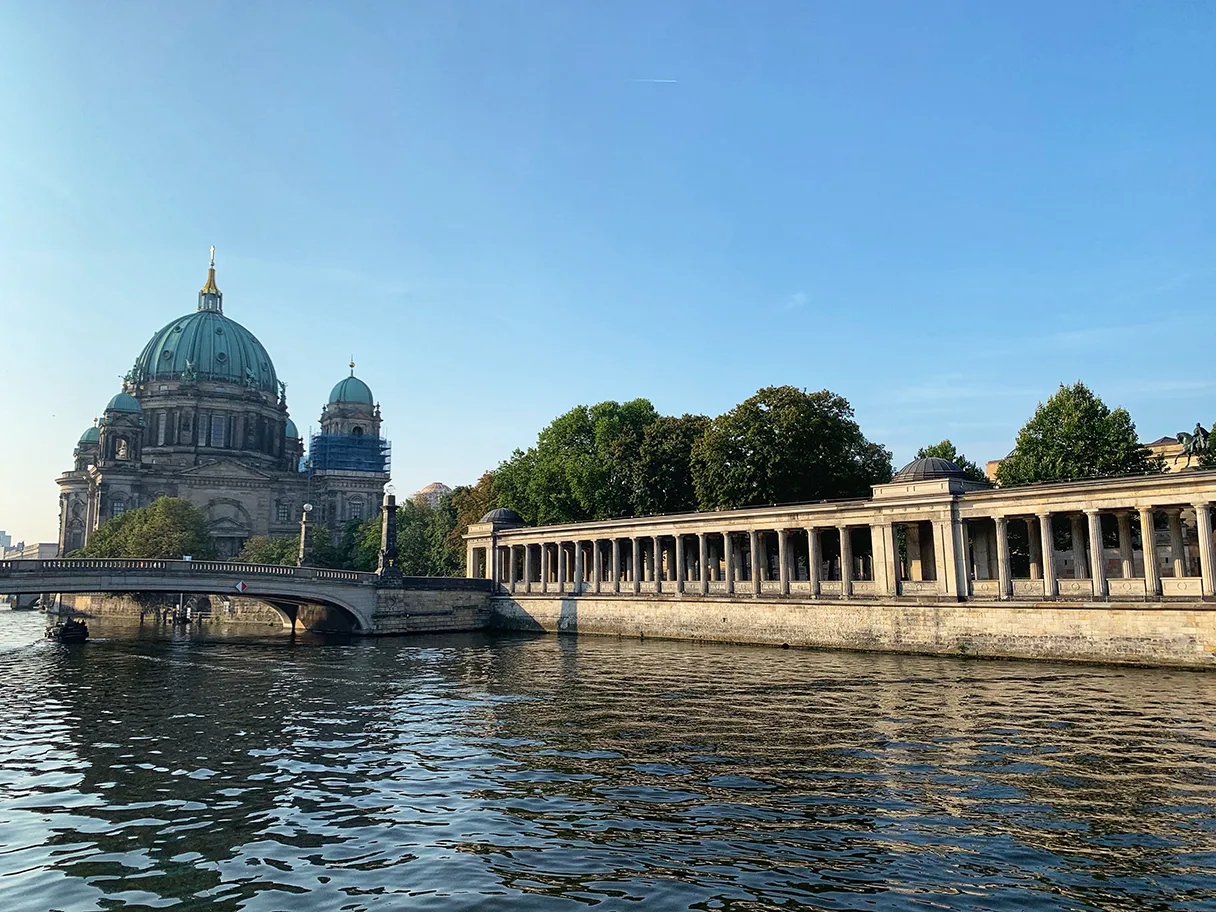 Original Berlin walks, Blick auf die Museumsinsel mit dem Berliner Dom und den Kollonaden im Sonnenuntergang, im Vordergrund fließt die Spree