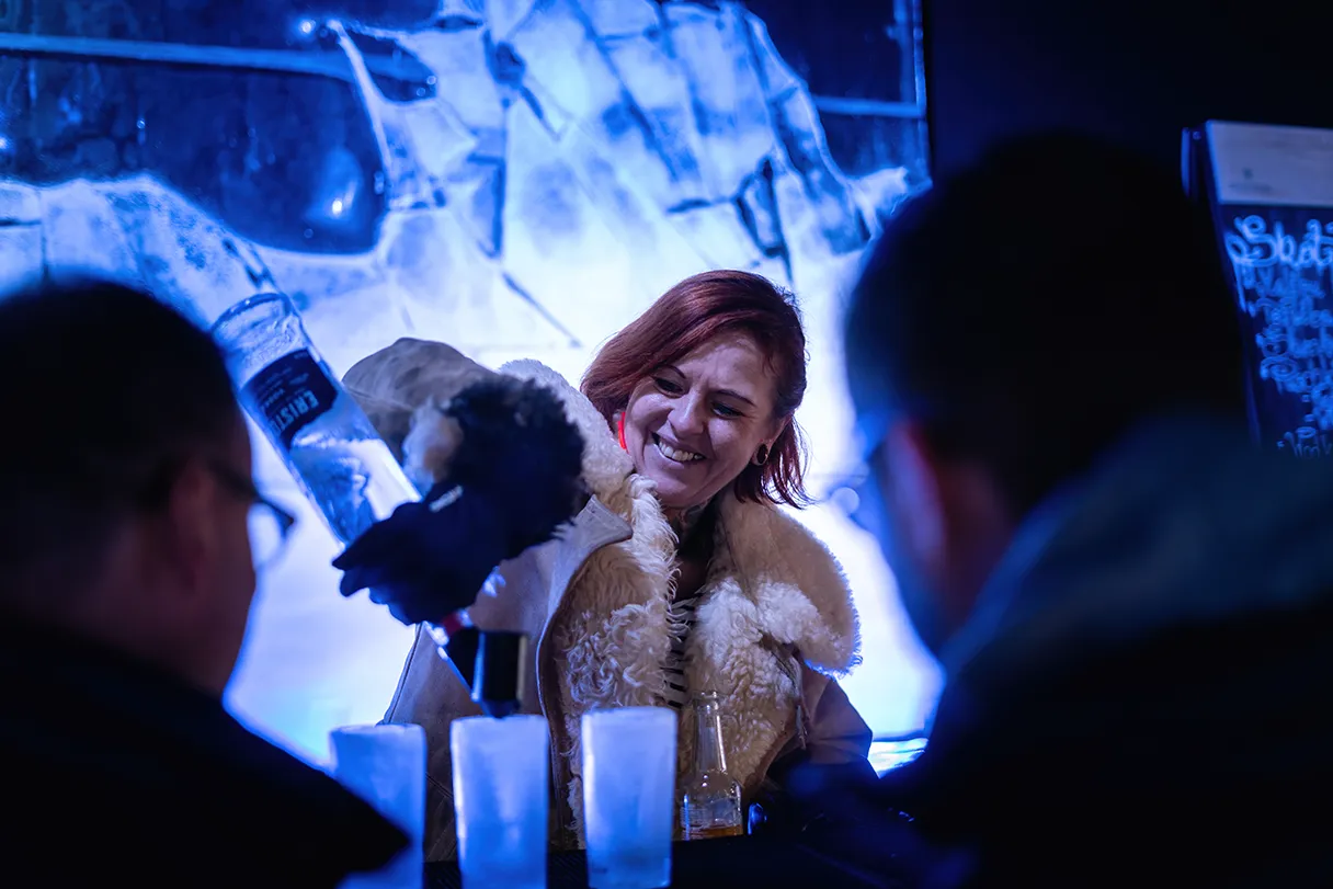 Berlin Icebar, Frau hinter der Bar gießt aus einer Flasche Alkohol in gefrorene Eis-Gläser