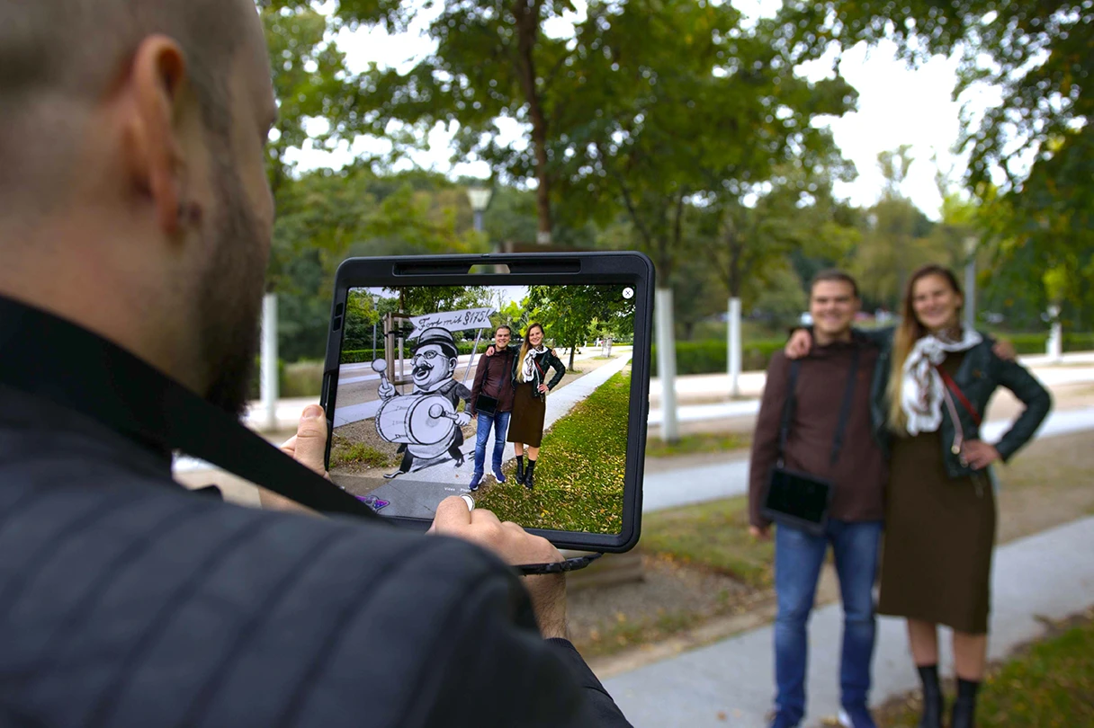 Mann mit Tablet positioniert ein Paar auf der Straße ins Tablet und daneben erscheinen virtuelle Sachen