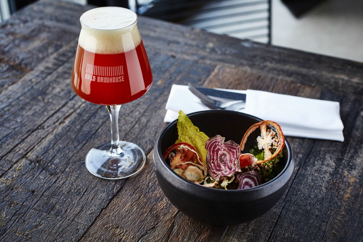 BRLO, bowl with salad stands on a table, next to it is a glass of craft beer