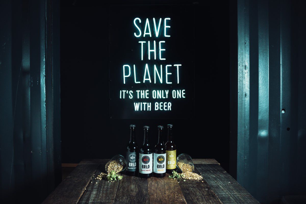 BRLO, Schild mit Save the Planet it's the only one with beer an der Wand, davor stehen verschiedene BRLO Bierflaschen