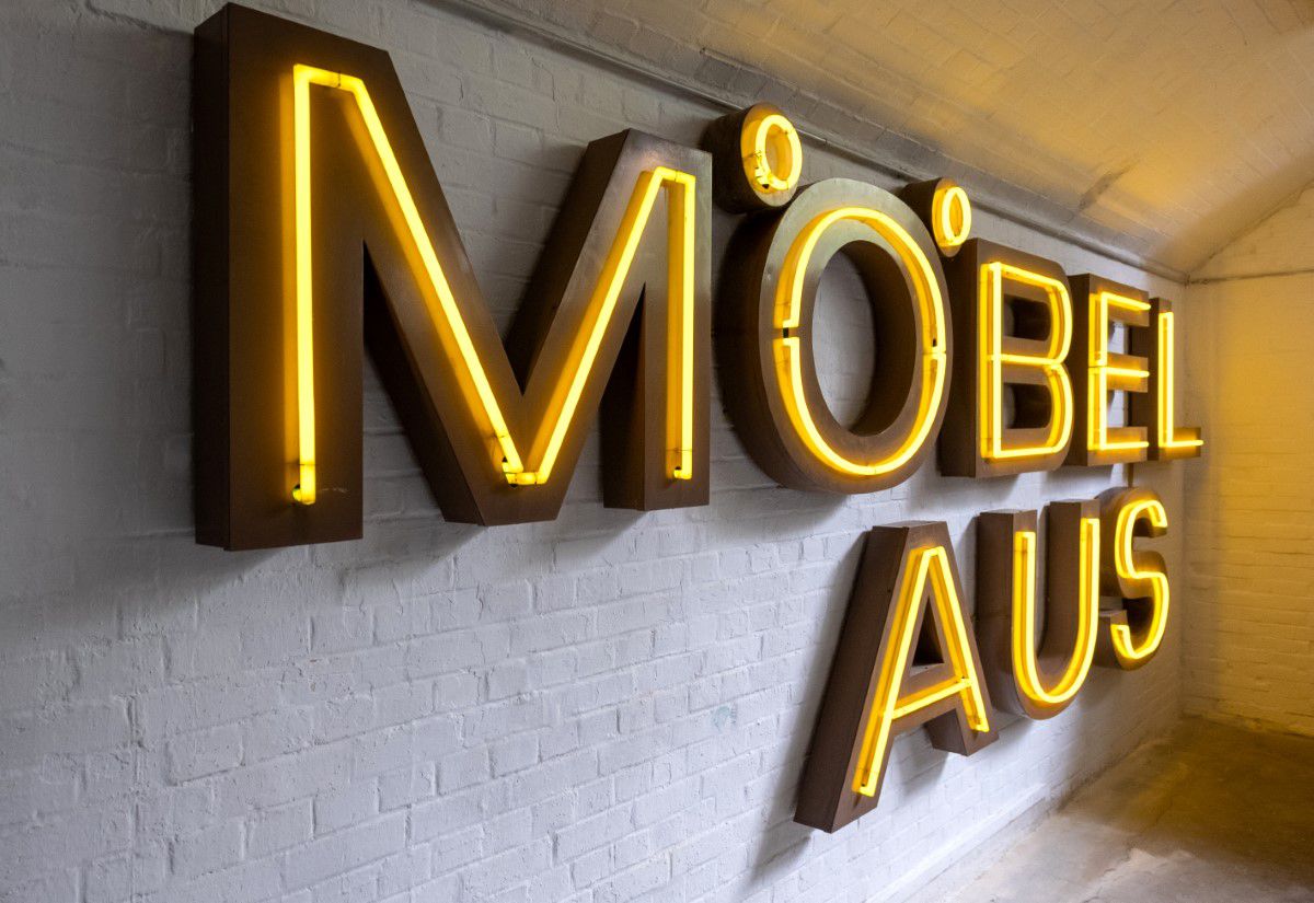 Buchstabenmuseum Berlin, gelbe Neonröhren, ergeben das Wort Möbelhaus, hängt an der Wand