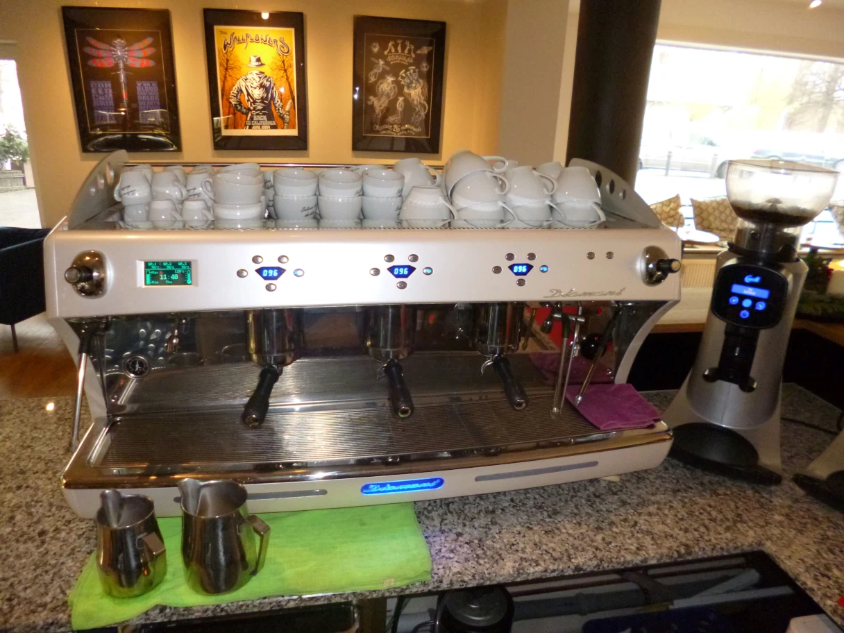 Café La Mouche, Kaffemaschine, mehrere weiße Tassen liegen gestapelt auf der Maschine