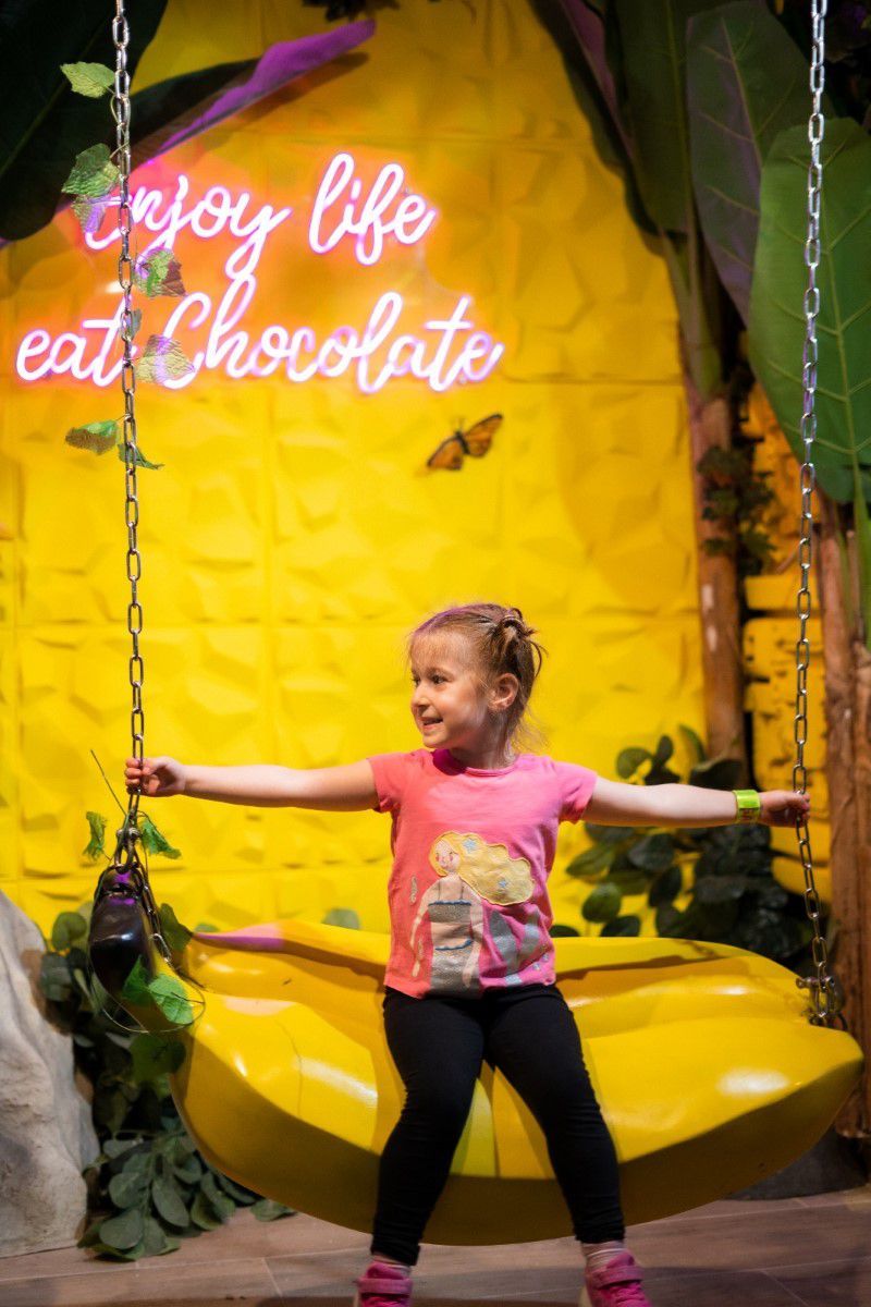 Chocolate Museum Vienna, kleines Mädchen sitzt auf einer Bananenschaukel