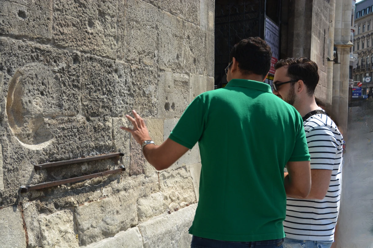 CityRiddler, zwei Männer stehen vor einer Kirchentür und schauen sich die Kirchenwand an, um ein Rätsel zu lösen