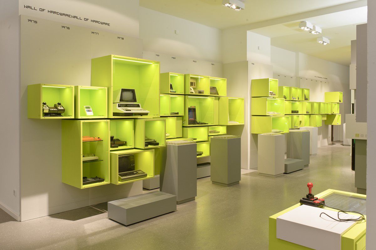 Computerspielemuseum, Eingangsbereich, Wall of Hardware, in grünen Vitrienen stehen verschiedene Computer aus unterschiedlichen Jahrezehnten