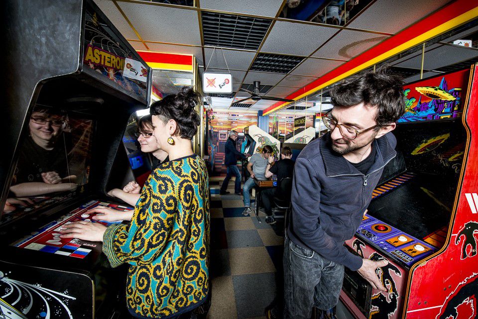 Computerspielemuseum, zwei Besucher stehen in der Arcadehalle und spielen Computerspiele
