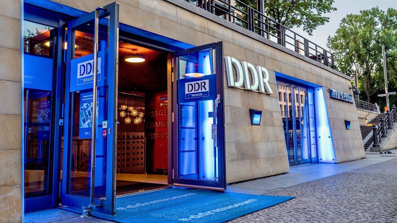 DDR Museum Eingangsbereich, blaues Licht an den Türen, DDR Schriftzug an der Außenfassade