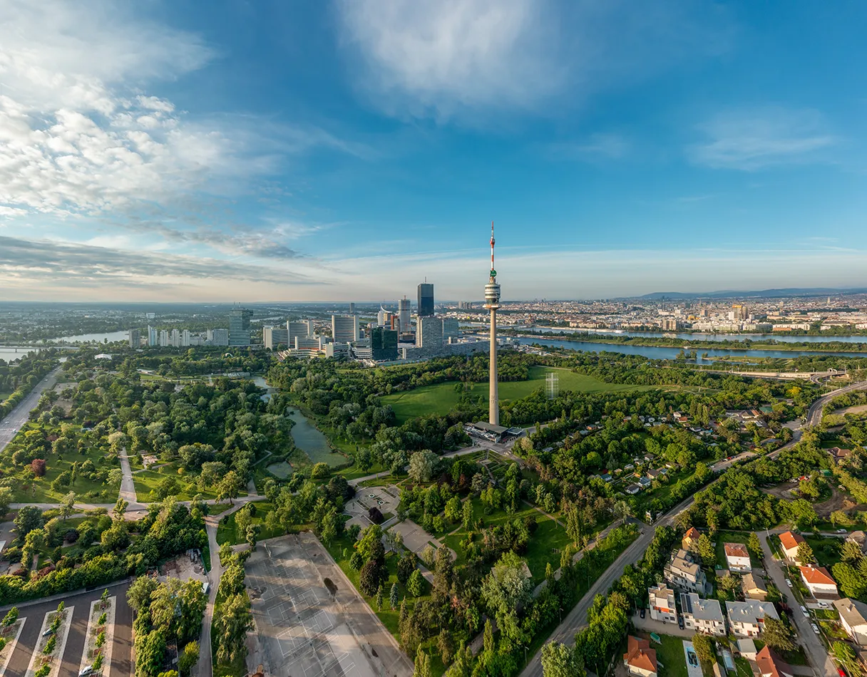 Donauturm. Panoramasicht aus der Vogelperspektive auf den Donauturm. Ringsherum ist sehr viel grün des Donauparks zu sehen. Sonniger Tag mit blauem Himmel und Sonnenschein.