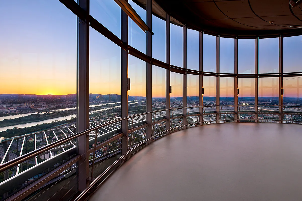 Donauturm. Blick auf die Innenterrasse. Große verglaste Front und im Hintergrund geht die Sonne unter.