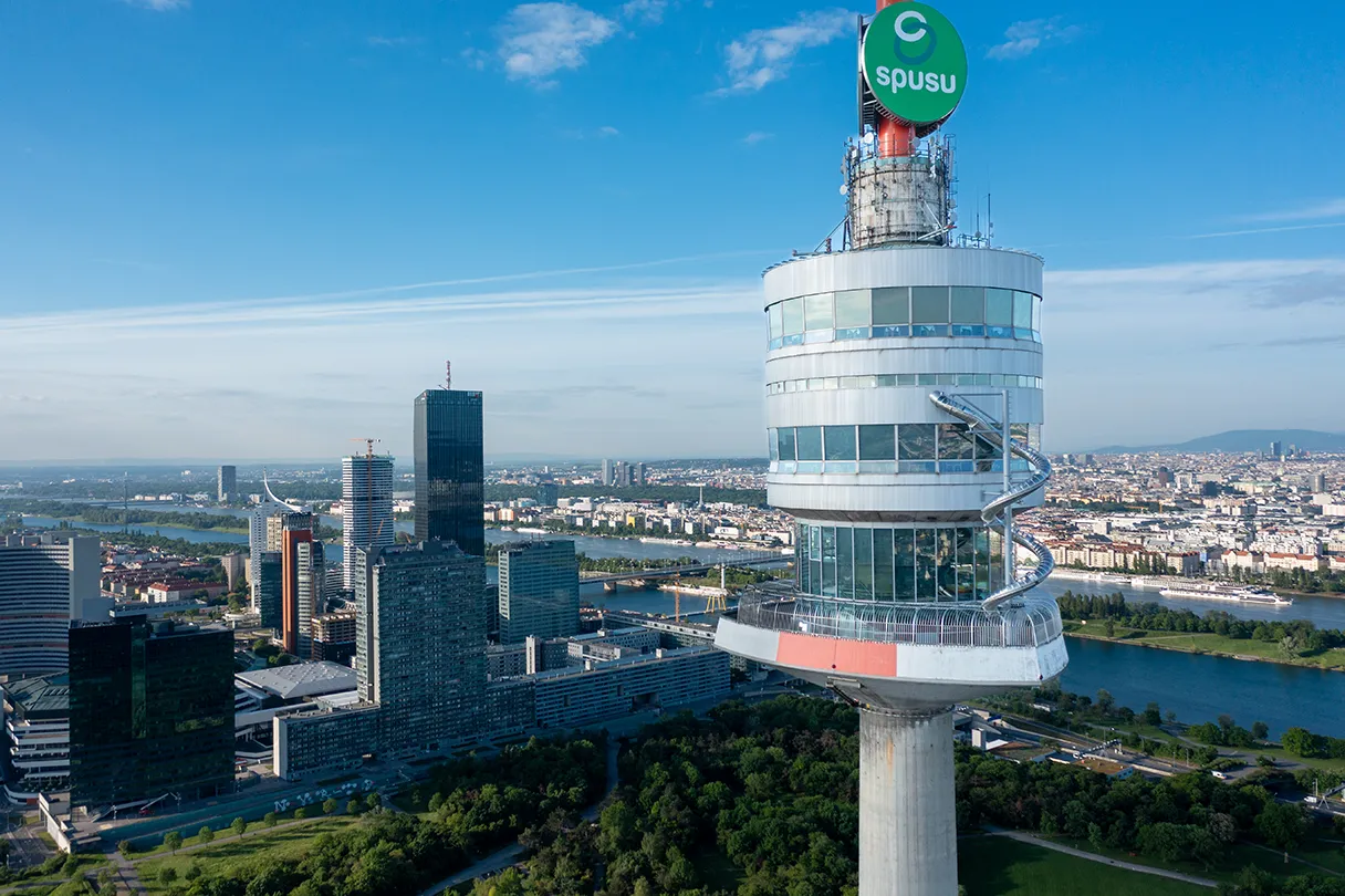 Donauturm. Panoramasicht aus der Vogelperspektive auf den Donauturm. Sonniger Tag. Im Hintergrund ist die Donaucity mit den Hochhäusern zu sehen. Man erkennt die Rutsche am Donauturm.