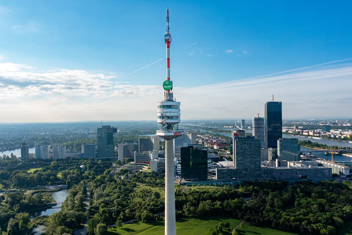 Donauturm. Panoramasicht aus der Vogelperspektive auf den Donauturm. Sonniger Tag. Im Hintergrund ist die Donaucity mit den Hochhäusern zu sehen.