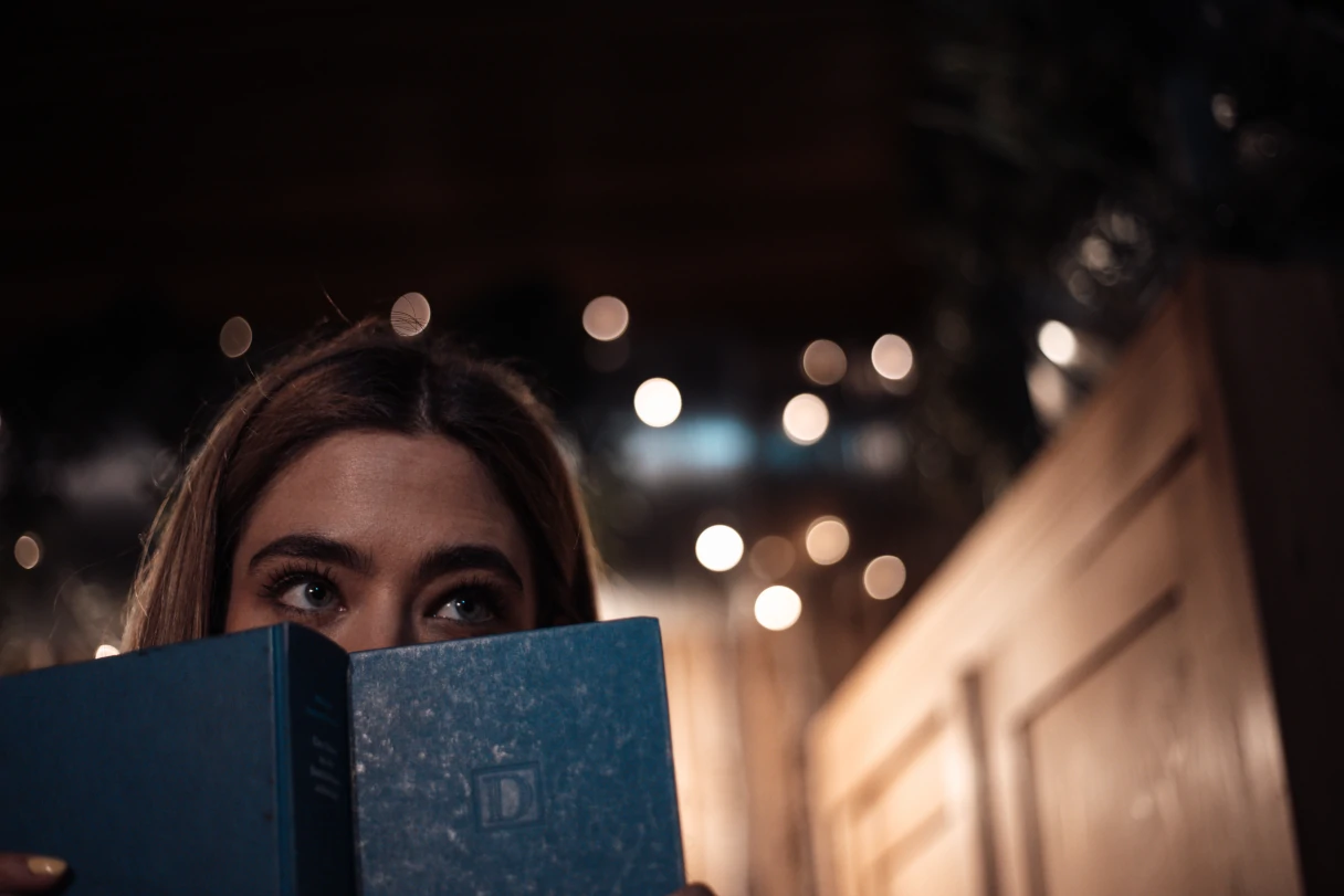 Escape Mission, Vienna, a woman holds a book in front of her face, only her eyes are recognizable, blurred background