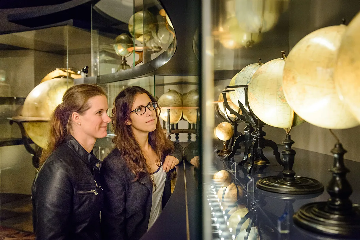 Globe Museum, Vienna, two women standing in the museum looking at the brightly lit globes