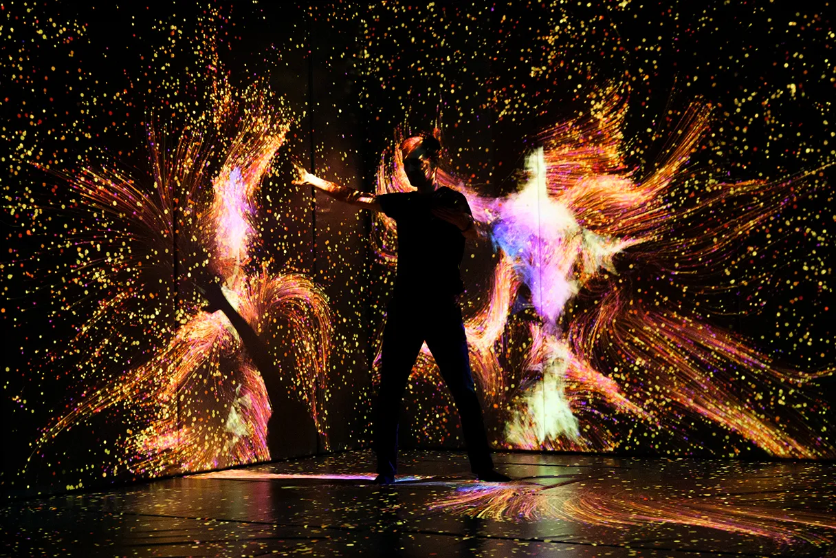 IKONO Berlin, room in which digital art is projected on the wall, a man interacts with it, which adapts to his movements