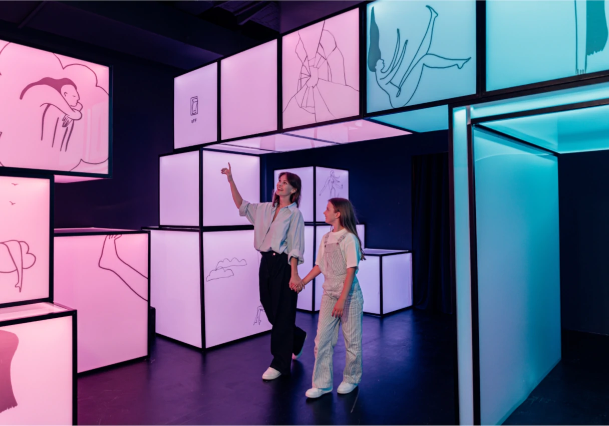 IKONO Vienna, mother and daughter walk hand in hand through the museum, colorful neon cubes are stacked next to them