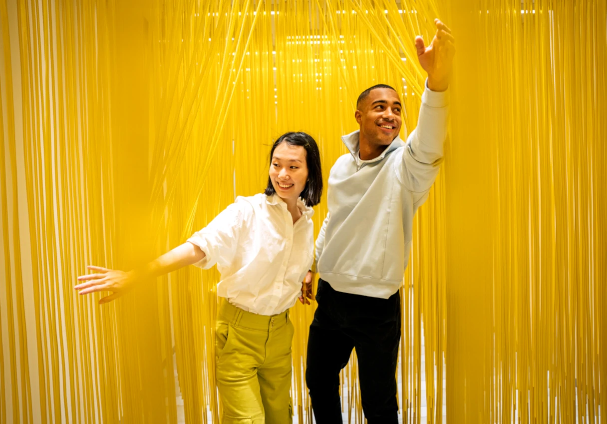 IKONO Vienna, man and woman walk through a yellow curtain and laugh