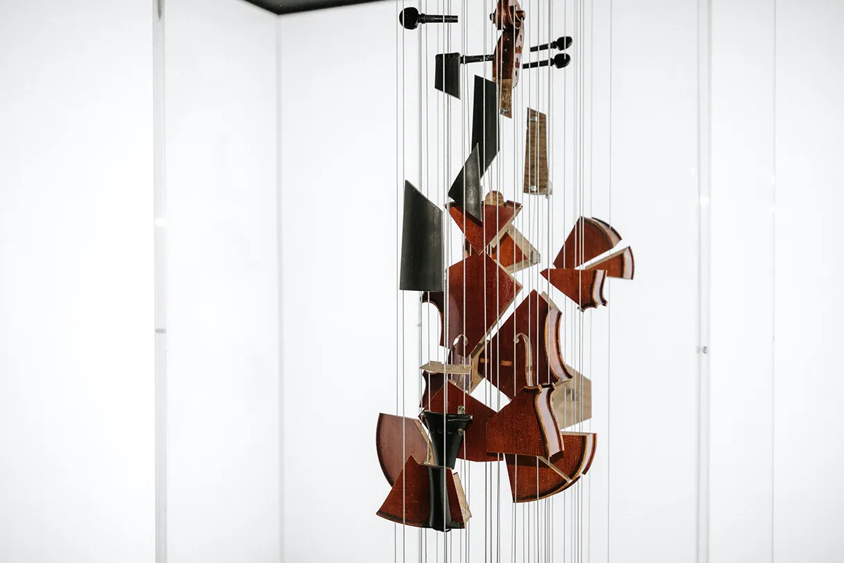 Johann Strauss Museum. View of the exhibition. A violin is suspended from the ceiling in various elements. Depending on which perspective you look from, you can either see the individual parts or the entire violin.