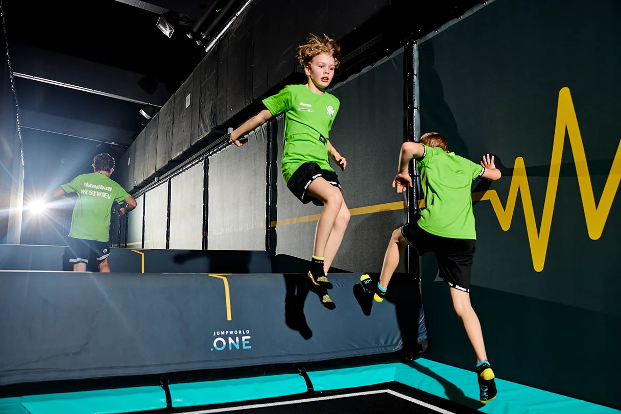 Jumpworld One, zwei Jungs in grünen T-Shirts und schwarzen Hosen springen auf dem Trampolin hin und her