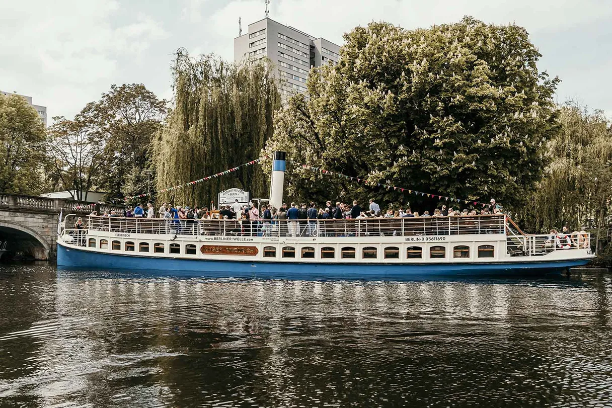 Kaiser Friedrich, Schiff, Berlin, Blick auf das Schiff im Seitenprofil, im Hintergrund sind viele Bäume, ein Hochhaus guckt dazwischen vor